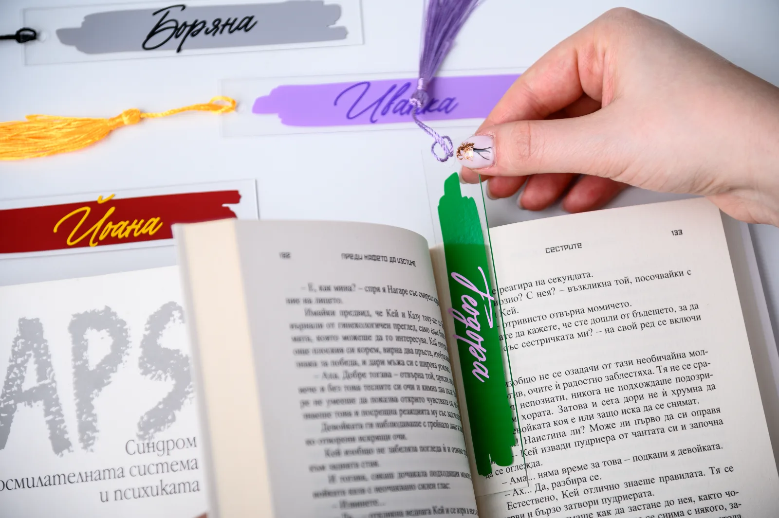 Персонализиран книгоразделител с име и пискюл, поставен в книга по време на четене